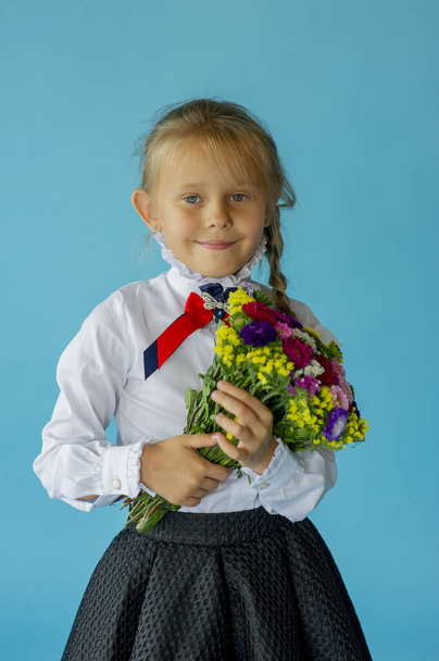 six years old girl in white t-shirt isolated on blue studio background, pretty european appearance child pose indoor smiling look at camera, generation Z concept. Girl schoolgirl on a blue background - Photo, Image