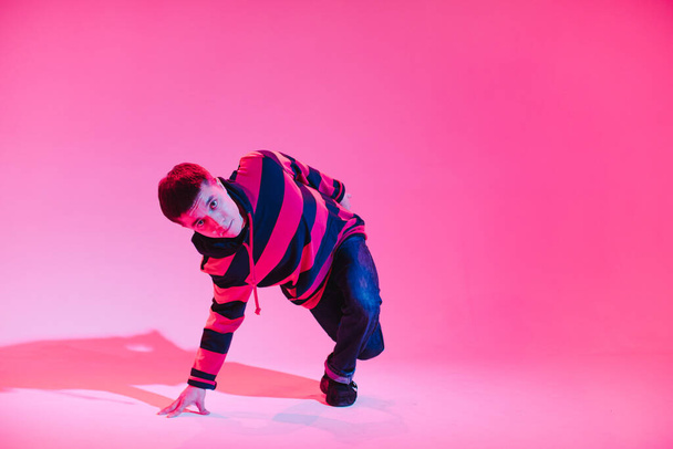 Young Man in a Jumper Dancing Contemporary Dance in Studio. Breakdancing. Dance School Poster. Copy Space. Battle competition announcement. Pink and Blue Background. - Fotoğraf, Görsel