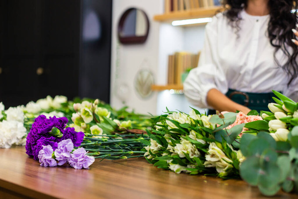 Aantrekkelijke jonge vrouw bloemist werkt in een bloemenwinkel. - Foto, afbeelding