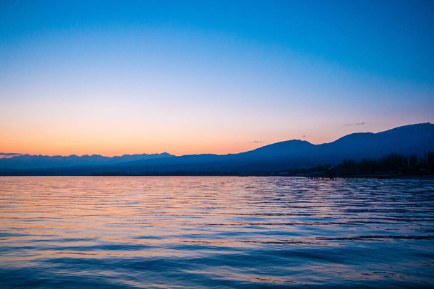 Beautiful lake, silhouette of the mountains on the sunset with blue skys and reflection of the water - Φωτογραφία, εικόνα
