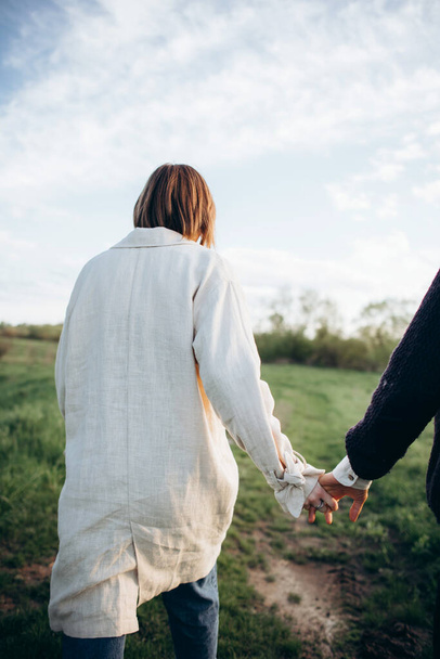 Young hipster couple walking in the field holding hands. - Foto, afbeelding