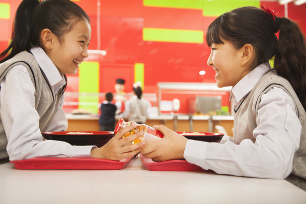 学校の食堂で昼食を食べながら話す女の子 - 写真・画像