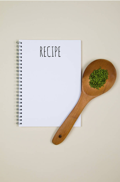 Wooden spoon with some food spice and a blank notebook page with quote Recipe - Photo, Image