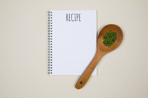 Ξύλινο κουτάλι με κάποια μπαχαρικό τροφίμων και μια κενή σελίδα σημειωματάριο με απόσπασμα Συνταγή - Φωτογραφία, εικόνα