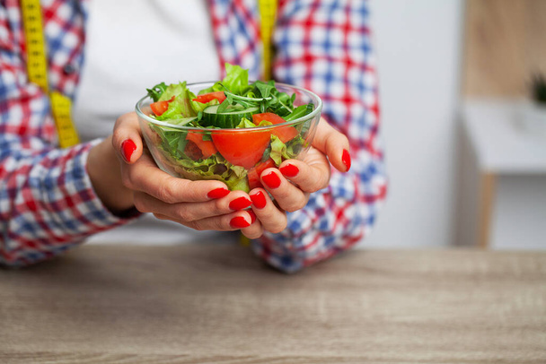 Kadın şeffaf tabakta taze sebze salatası tutuyor. - Fotoğraf, Görsel