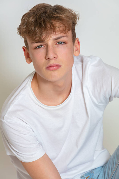 White background studio photograph of young thoughtful moody boy male teen teenager young adult wearing jeans and a white t-shirt - Foto, afbeelding