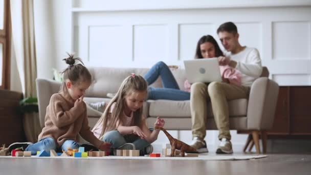 Kleine Kinder spielen Spielzeug, während Eltern Computer benutzen. - Filmmaterial, Video