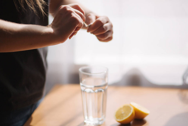Les mains des femmes mettent l'aspirine dans le verre avec de l'eau. Concept de coronavirus
 - Photo, image