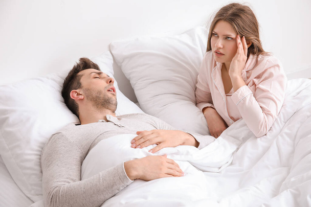 Junge irritierte Frau im Bett mit schnarchendem Ehemann zu Hause - Foto, Bild