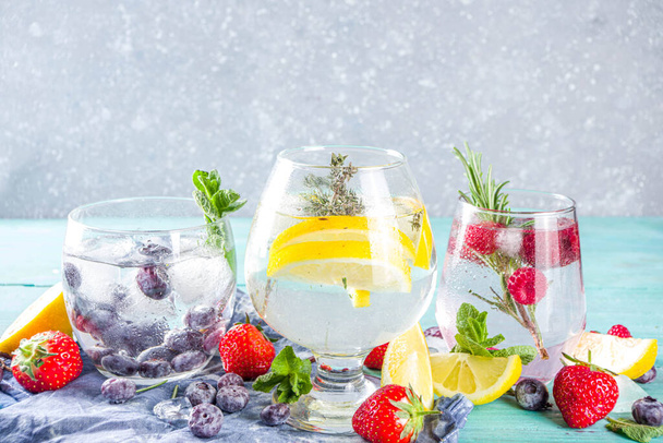 Koncept letních studených drinků. Ovoce a bobule gin tonic koktejl, nebo infuze vody limonáda moktail, s čerstvým borůvkem, malina, citron a bylinky, modrá zelená staré dřevěné pozadí kopírovat prostor - Fotografie, Obrázek