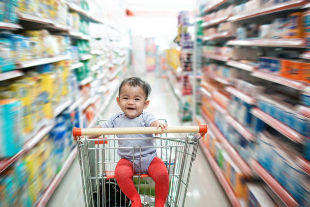 onnellinen vauva istuu yksin ostoskärryissä
 - Valokuva, kuva