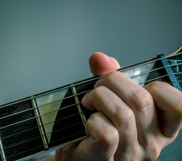 Dedo na posição de E acorde menor. Mão segurando uma guitarra
 . - Foto, Imagem