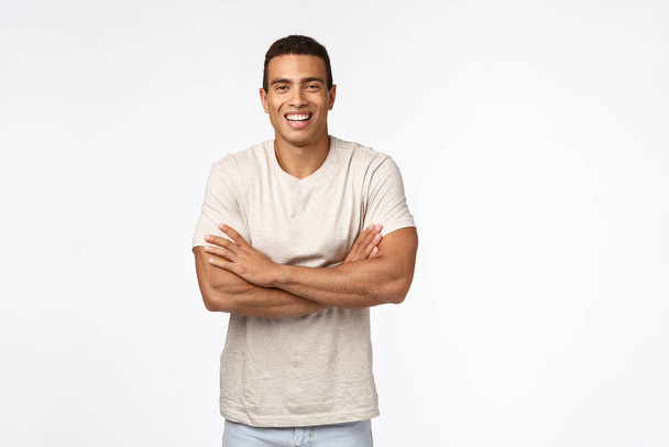 Elämäntapa, urheilu ja ihmisten käsite. Komea onnellinen nuori latino kaveri rento t-paita, rajat kädet rinnassa, osoittaa vahvat lihakset, nauraa ja hymyilee huoleton, nauttia hauska keskustelu
 - Valokuva, kuva