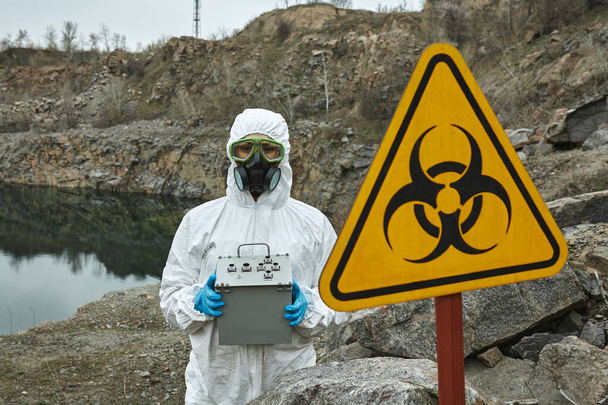 Girl in protective overalls on the nature. Biological protection suit, mask and glasses on the face. Personal protective equipment to prevent transmission of the virus. The concept of coronavirus, pandemic, flu and quarantine. Symbol of biohazard. - Photo, Image