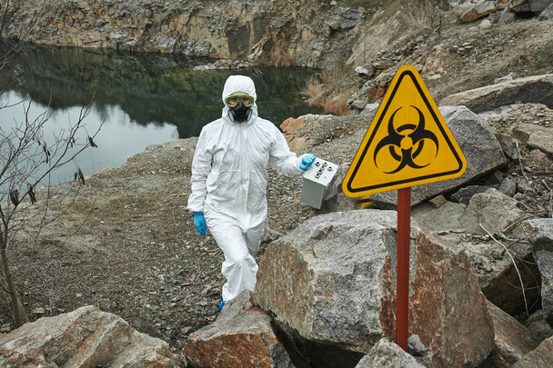 Girl in protective overalls on the nature. Biological protection suit, mask and glasses on the face. Personal protective equipment to prevent transmission of the virus. The concept of coronavirus, pandemic, flu and quarantine. Symbol of biohazard. - Photo, Image