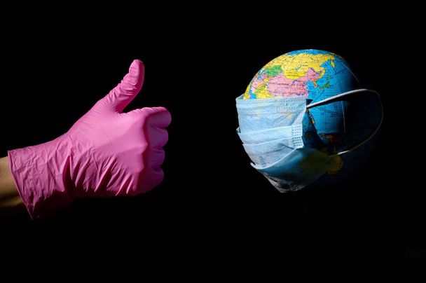 Main féminine et la terre avec masque contre le virus
 - Photo, image