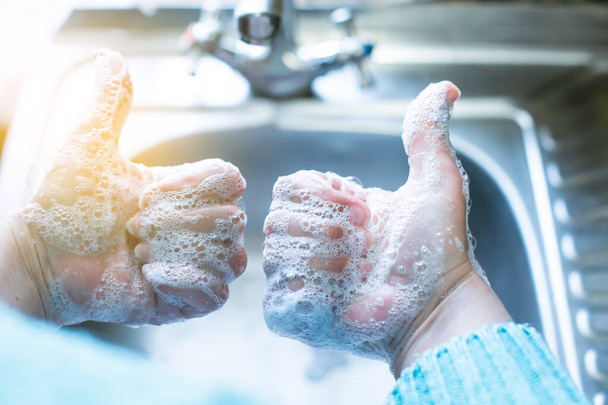 Soapy hands show like, against the background of a metal sink, in the light from the window - Photo, Image