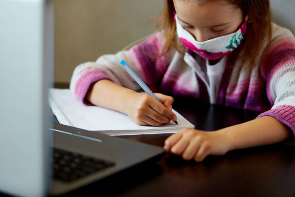 Schulmädchen lernt zu Hause mit einem Notizbuch und macht Hausaufgaben. Online-Fernunterricht. Coronavirus Heimschulkonzept, Quarantäne. - Foto, Bild