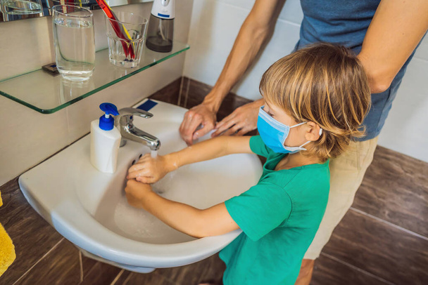 Dad teaches his son to wash his hands properly. Dad and son in medical masks because of coronovirus. Epidemic. Stay home. Wash your hands - Фото, зображення