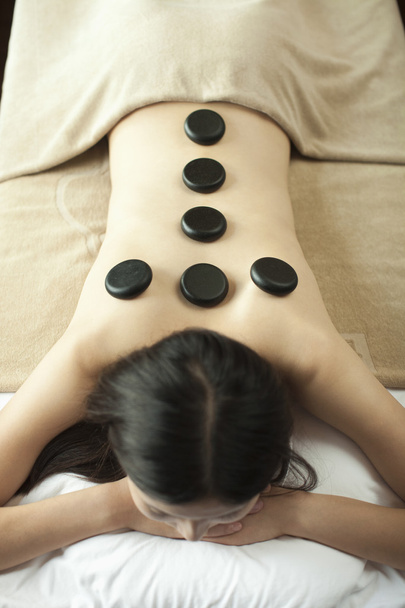 Mujer joven recibiendo masaje de piedra caliente
 - Foto, Imagen