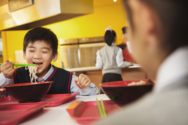 Un écolier mange des nouilles à la cafétéria de l'école
 - Photo, image