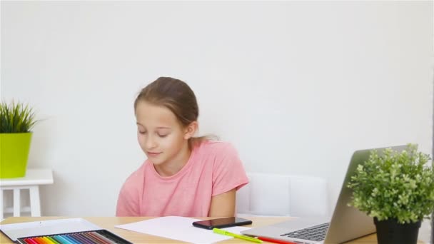 Серйозна школярка сидить за столом з ноутбуком і підручником і робить домашнє завдання. Навчання з дому
 - Кадри, відео