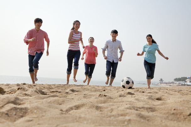 jonge vrienden spelen voetbal op het strand - Foto, afbeelding