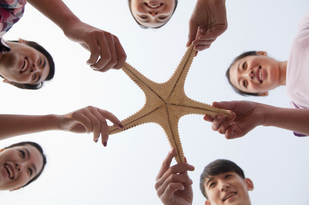 Grupo de amigos sosteniendo una estrella de mar
 - Foto, Imagen