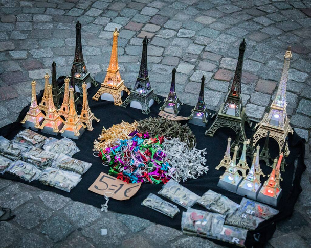 Een top hoek close-up shot van verschillende souvenirs, zoals miniatuur Eiffeltorens, sleutelhangers, en magneten weergegeven op de grond, te koop aangeboden, Parijs - Foto, afbeelding