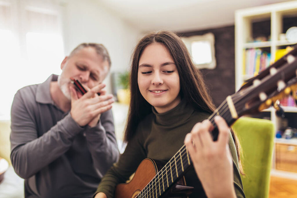 Οικογένεια παίζει μουσικά όργανα στο σπίτι διασκεδάζοντας. - Φωτογραφία, εικόνα