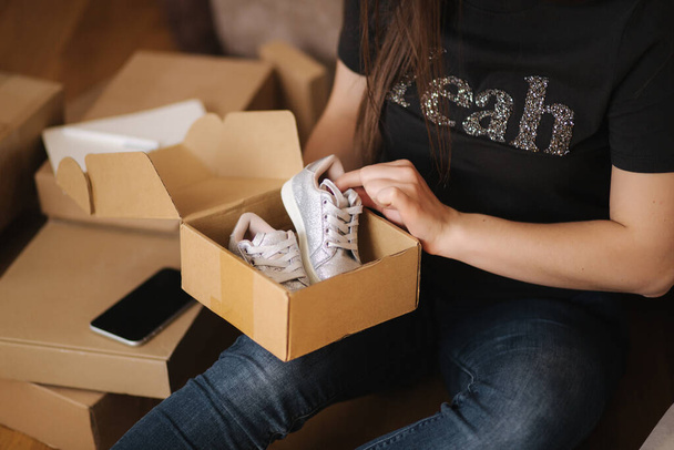 Young woman open new parcel with clothes. Woman hepl to sell secound hand goods - Photo, Image