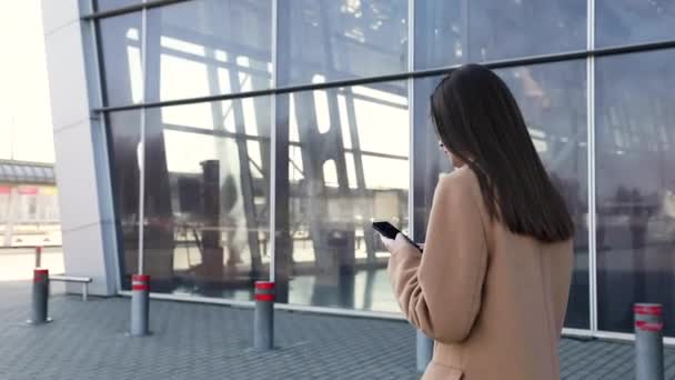 Young Businesswoman Using SmartPhone, Going to Work in the Sunny Morning City. SLOW MOTION. Shot. Attractive Professional Business Woman with a cell phone in a city. Lens Flare. - Materiał filmowy, wideo