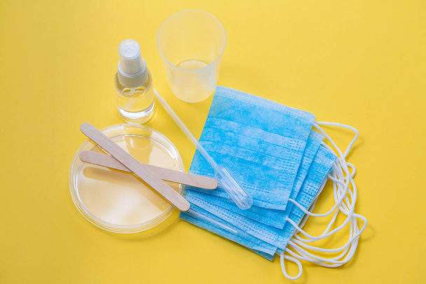 medical mask, plastic cups and other objects on yellow background - Φωτογραφία, εικόνα