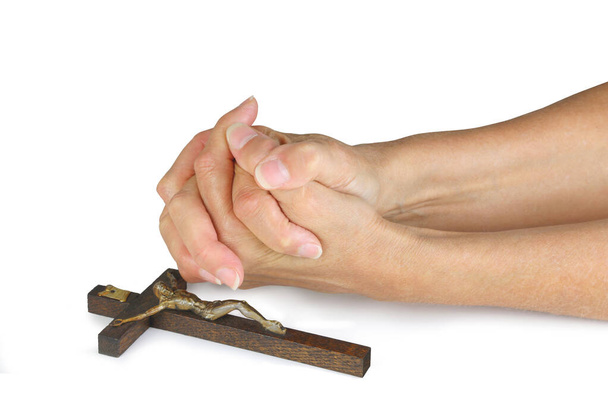 Modląc się o pokój tej Wielkanocy - żeńskie dłonie w pozycji modlitewnej złożone obok drewnianego krzyża odizolowanego na białym tle - Zdjęcie, obraz