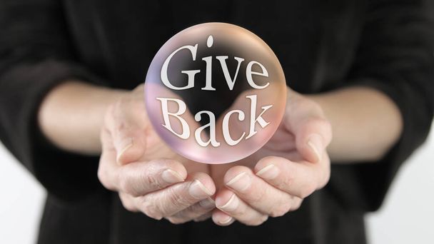 Give Back Campaign Bubble Concept - velký průhledný duhový barevný míč zobrazující slova Dát zpět uvnitř plovoucí nad ženské ruce    - Fotografie, Obrázek