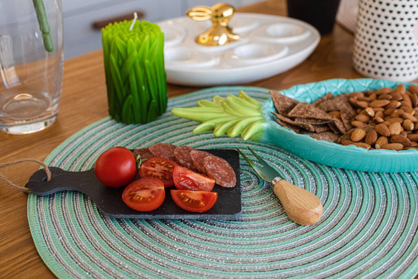 Tomates, salchichas repartidas, galletas en el plato y una vela de hierba verde en la cocina
 - Foto, Imagen