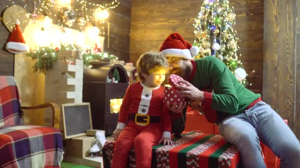 Father Santa Claus wishes Merry Christmas for son. Happy child with Christmas gift box. Santa Claus gifting gift. - Metraje, vídeo
