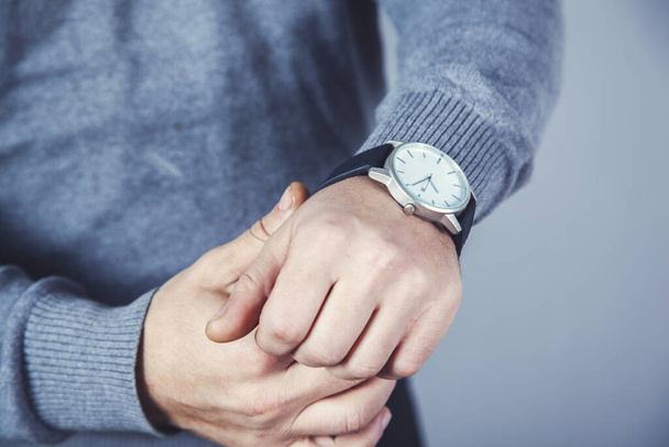 man hand horloge op de grijze muur achtergrond - Foto, afbeelding