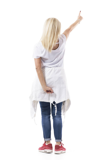 Rückenansicht einer blonden Frau mittleren Alters, die mit erhobenem Zeigefinger den Knopf im interaktiven Touchscreen drückt. Volle Körperlänge isoliert auf weißem Hintergrund. - Foto, Bild