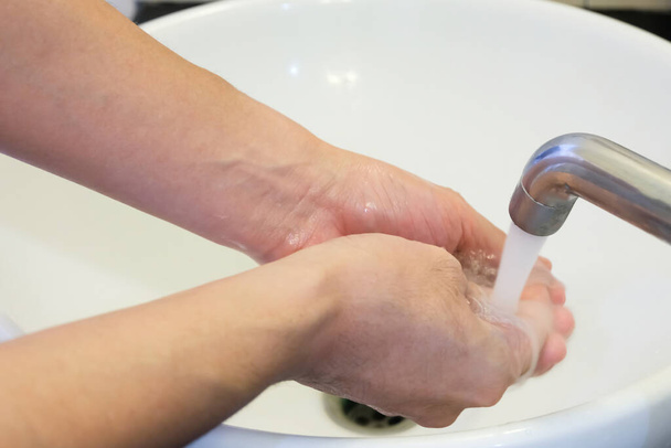 石鹸と水で手を洗うアジアの男性の選択的な焦点をクリーンアップします。コロナウイルス、 Covid-19パンデミックの間のウイルスや病気を予防し、保護するための個人衛生. - 写真・画像