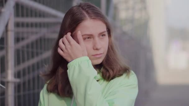 A girl in a tracksuit walks around the stadium straightening her hair - Filmmaterial, Video