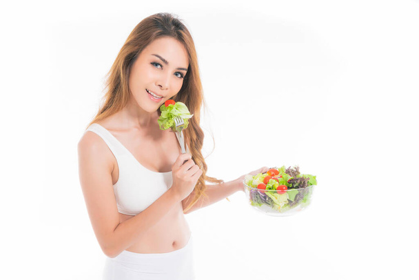 Красива азіатська молода жінка здорова їжа в білому спортивному бюстгальтері їсть салати зі здоровою їжею на білому тлі
. - Фото, зображення