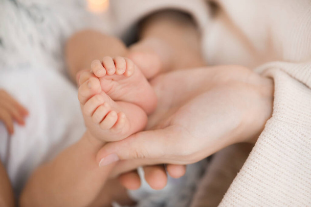 Moeder 's handen houden kleine voeten van kleine baby, close-up - Foto, afbeelding