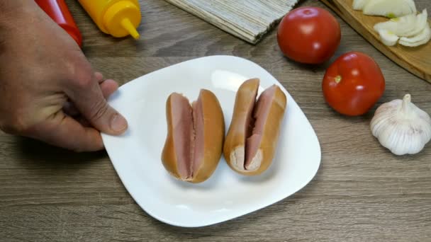 Gekookte worsten op witte plaat worden bewaterd met ketchup en mosterd uit buizen. Huiskeuken. - Video