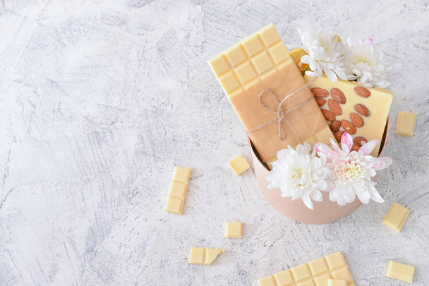 Caixa de presente com chocolate branco doce e flores na mesa
 - Foto, Imagem