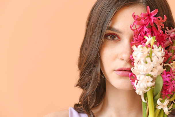 Arka planda sümbül çiçekleri olan güzel genç bir kadın. - Fotoğraf, Görsel