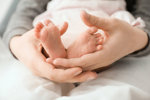 Η μητέρα κρατάει μικροσκοπικά πόδια του μωρού, κοντά. - Φωτογραφία, εικόνα