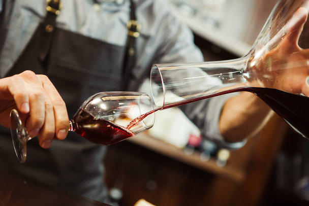 Sommelier pouring wine into glass from mixing bowl. Male waiter - Zdjęcie, obraz