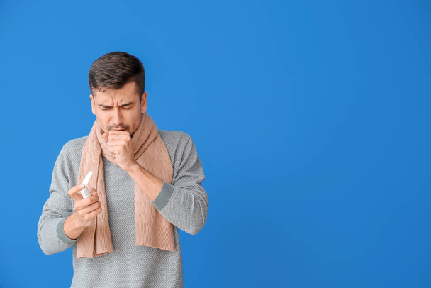 Coughing young man with inhaler on color background - Foto, immagini