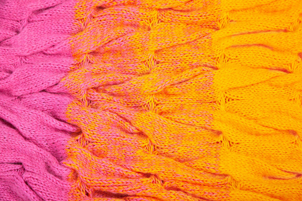 the texture of the fabric, knitted with needles, pigtail pattern, handmade. Color transition from pink to yellow, color gradient. Three-dimensional knitted pattern. Wool. Knitting needles, knitting for beginners. Knitting patterns. Knitting magazines - Photo, Image